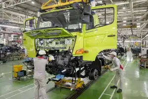 Proses perakitan truk Hino di pabrik Indonesia dengan teknisi sedang bekerja.